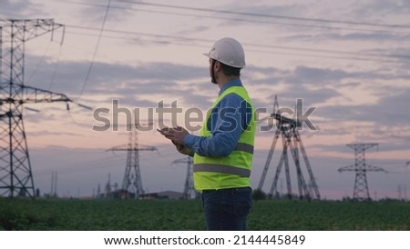 technology concept with high voltage power lines. electrical engineer helmet digital tablet sunset. power engineer power plant high voltage voltage energy. concept electrical engineer working sunset. Royalty-Free Stock Photo #2144445849