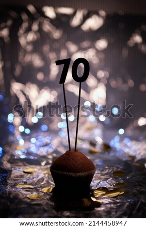Homemade anniversary cupcake with number 70 seventy and blurred bright background. Minimalistic birthday or anniversary gift card concept. High quality vertical image