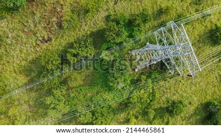 Aerial top down view high voltage steel power pylons in green field countryside. Flight over power transmission lines. Electric tower line, daylight, summer day. Royalty-Free Stock Photo #2144465861