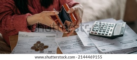 Close-up of woman's hands with empty wallet and utility bills. The concept of rising prices for heating, gas, electricity. Many utility bills, coins and hands in a warm sweater holding an open wallet Royalty-Free Stock Photo #2144469155