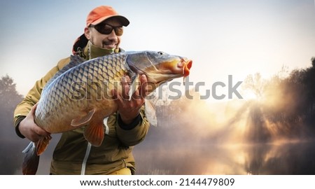 Fishing background. Young man hold big carp in his hands.	 Royalty-Free Stock Photo #2144479809