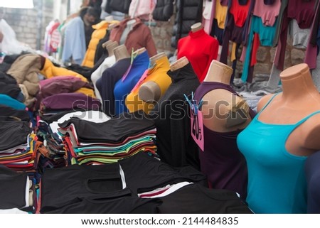 Street fashion, shopping at the street market. Inexpensive clothing displayed on mannequins in the stalls. Second hand clothing. Horizontal close-up.