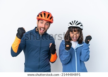 Young cyclist couple isolated on white background celebrating a victory