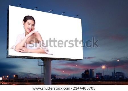 Portrait of beautiful charming young Asian woman posing facial and sitting with white table advertise on billboard blank for outdoor advertising poster or blank billboard for advertisement. Royalty-Free Stock Photo #2144485705