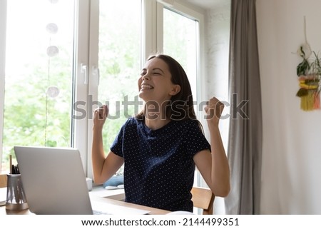 Cute woman celebrate great news read on laptop sit at desk with fists clenches looks excited feel unbelievable happy, student accomplish task, got scholarship, receive notice about lottery win concept Royalty-Free Stock Photo #2144499351