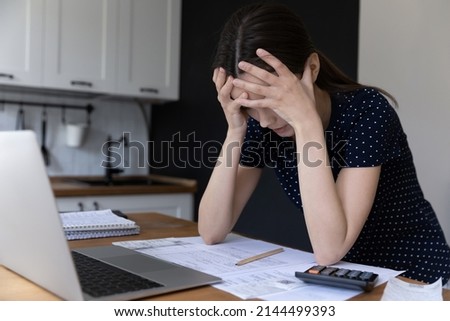 Close up upset young woman clasping her head lean at table with computer and heap of bills, feels stressed shocked due high taxes, money overspend, bank debt, lack of finances to pay utilities concept Royalty-Free Stock Photo #2144499393