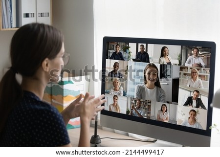 Businesswoman sit at workplace desk with computer, speak to colleagues, business team or clients use video conference application, diverse people on monitor screen view. Group video call event concept Royalty-Free Stock Photo #2144499417