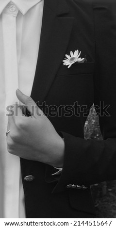 Close up photo of man in formal black suit with a white daisy in pocket square.
