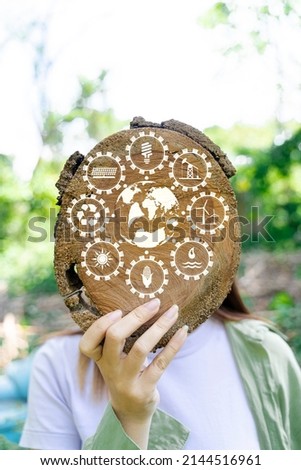 A woman holding a wooden plank with a circular shape leading up to her face and symbolized by an energy icon.