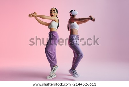 Happy young woman partying as a 3D avatar in the metaverse. Cheerful young woman having fun while wearing virtual reality goggles. Young woman enjoying a 3D simulation in a studio. Royalty-Free Stock Photo #2144526611