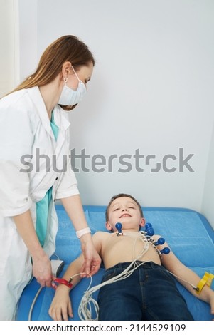 Female doctor doing electrocardiogram test for little boy in clinic