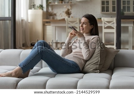 Positive beautiful smartphone user woman in casual having telephone call on speaker, giving voice command to virtual assistant, recording audio message on online chat. Communication concept Royalty-Free Stock Photo #2144529599