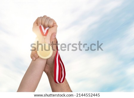 Close up photo of woman rising gold medal and man helping her. Supportive husband in worklife or business concept. Royalty-Free Stock Photo #2144552445