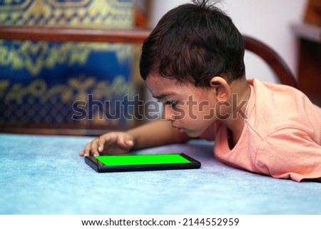 a toddler baby boy engaged in watching and exploring mobile phone.Screen time addiction concept image.