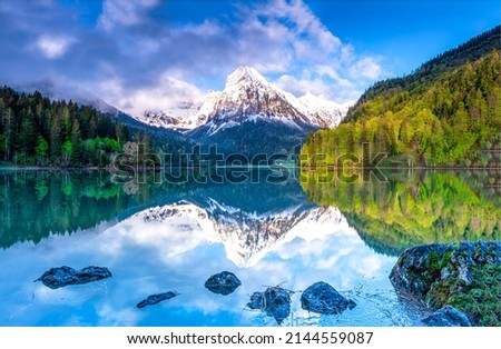 A mountain peak is reflected in a mountain lake. Beautiful mountain lake landscape. Mountain forest reflected in lake water. Forest lake in mountains Royalty-Free Stock Photo #2144559087