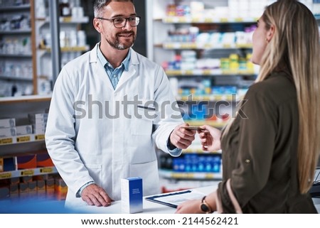 Yes, we do accept cards here. Shot of a young woman paying for merchandise with a credit card at a pharmacy. Royalty-Free Stock Photo #2144562421