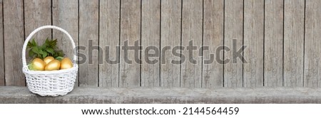 Easter banner, golden eggs in a white basket. Wooden background with copy space.