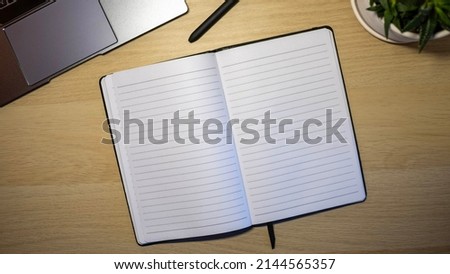 blank notepad with black pen on wooden table next to laptop