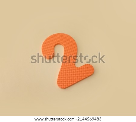 Flat lay orange number 2 sign on beige background