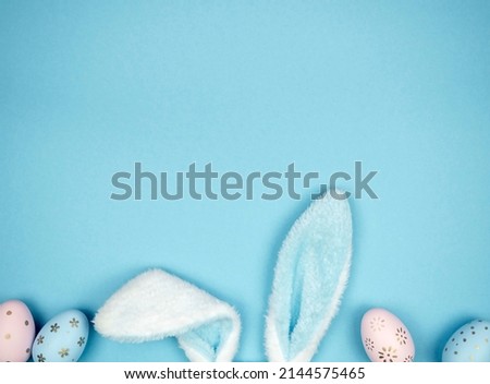 Hare ears with Easter eggs on a blue background. Easter concept. Space for text.