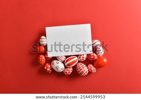 Easter banner with a blank sheet of paper and Easter red and white eggs on a bright red background. Copy space. Flat lay, top view.