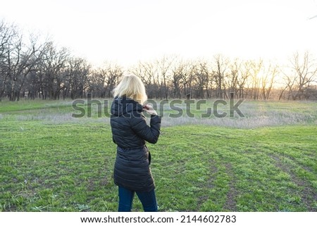 A woman with blonde hair admires the evening landscape at sunset.