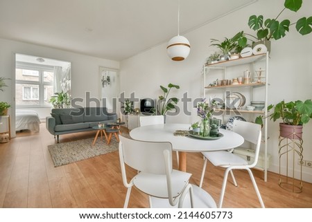 The interior of a spacious living room connected to a dining area and lots of house plants
