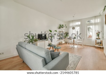 The interior of a spacious living room connected to a dining area and lots of house plants