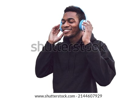 Portrait of smiling young african runner man in wireless headphones enjoying listening to music wearing black hoodie isolated on white background