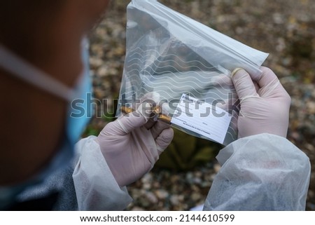 Close up on hands of unknown man forensic police investigator collecting evidence in the plastic bag at the crime scene investigation Royalty-Free Stock Photo #2144610599