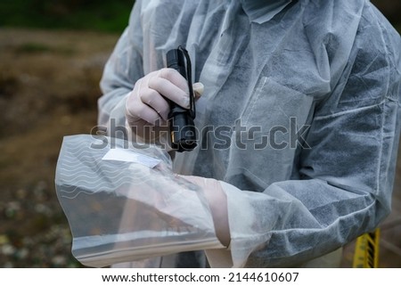 Close up on hands of unknown man forensic police investigator collecting evidence in the plastic bag at the crime scene investigation Royalty-Free Stock Photo #2144610607
