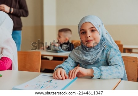 Group of children sitting at the school desk in the classroom. Happy Muslim school kids during the class. Group of young Islamic students.	