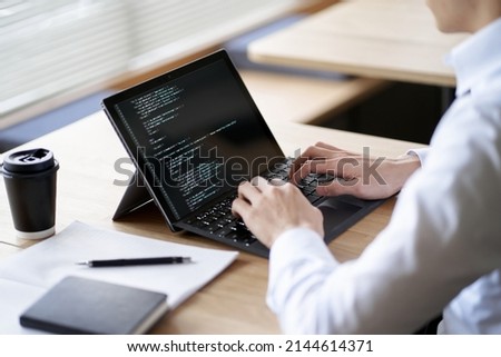 Asian programmer writing code on a laptop Royalty-Free Stock Photo #2144614371