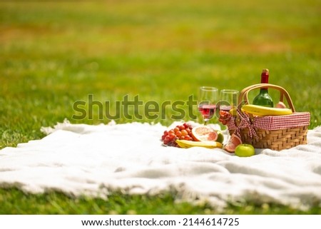 Picnic basket with fruit wine on a bedspread in the garden.
