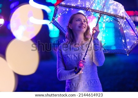Walk through the night rainy city with an umbrella and lights. Creative photo