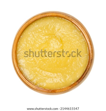 Apple sauce in a wooden bowl. Commercially processed applesauce, a yellow sauce made of peeled and cooked apples. Inexpensive and widely consumed in North America and parts of Europe. Macro food photo Royalty-Free Stock Photo #2144615547