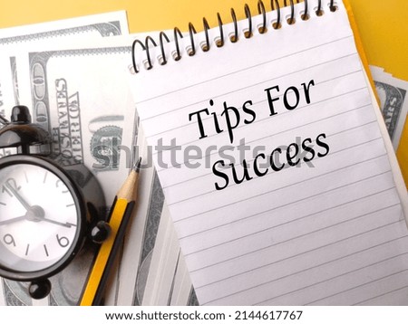 Alarm clock,pencil and banknotes with text Tips For Success on yellow background