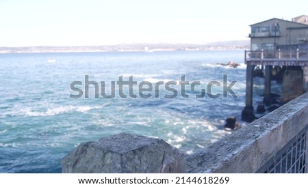 Waterfront wooden boardwalk in Monterey, California USA. Beachfront promenade on piles, pillars or pylons by ocean sea water and bay aquarium on Cannery Row street. Tourist vacations waterside resort. Royalty-Free Stock Photo #2144618269