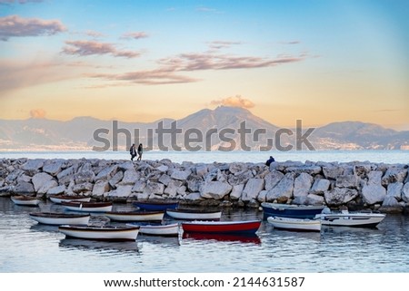 Wiew over fish boats embarked in the bay of Napoli on a gloomy spring evening. Napoli waterfront with Napoli hills and buildings on the background. Italy Royalty-Free Stock Photo #2144631587