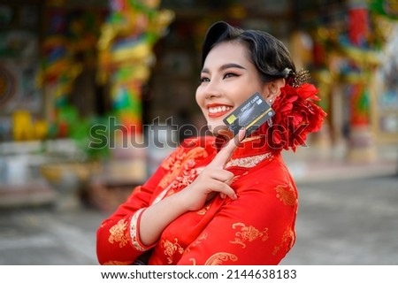 Portrait Asian beautiful woman wearing a cheongsam smiling and poses show credit card at shrine on Chinese New Year, copy space
