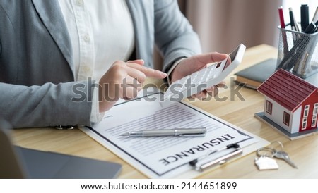 Insurance concept the estate broker pressing a calculator to calculate the price of the property. Royalty-Free Stock Photo #2144651899