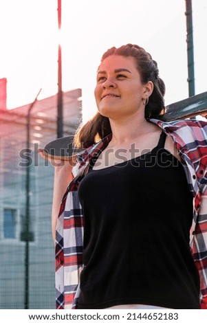 Cute millennial woman smile happy walking down the street with her skateboard. sun backlight and freedom rebel independent concept. Spending day for active board hobby