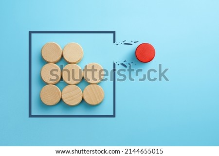 Concept of overcoming barriers, goal, target. Red wooden cube breaking through obstacle on blue background Royalty-Free Stock Photo #2144655015