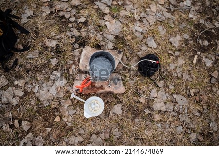 Water boils in a pot, tourist utensils, camp cooking on a hike, spring trekking through the forest, a top view of the camp kitchen. High quality photo