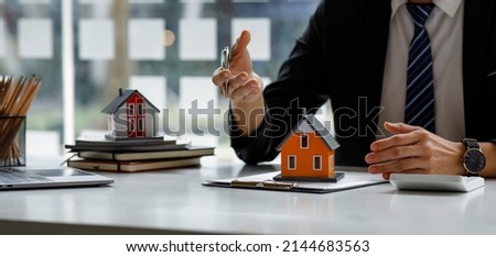 Real estate broker agent presenting and consult to customer to decision making sign insurance form agreement, buy and sell home model, concerning mortgage loan offer for and house insurance Royalty-Free Stock Photo #2144683563