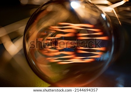 A bright fiery powerful glass incandescent lamp illuminates a dark room around with a fiery orange light