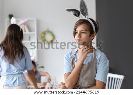 Thoughtful boy with bunny ears and brush during master-class in art