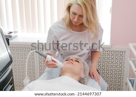 Rejuvenation facial treatment isolated on white. Model gets lifting therapy massage at SPA beauty salon. Exfoliate, rejuvenate and hydrate. Cosmetology. Close up, selective focus. Royalty-Free Stock Photo #2144697307