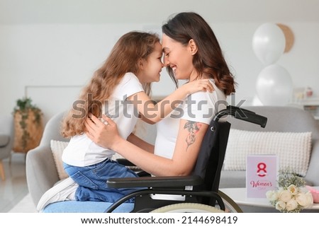 Little girl and her mother in wheelchair on International Women's Day at home Royalty-Free Stock Photo #2144698419