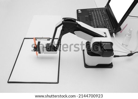 Futuristic robotic arm with pen and blank paper sheet at exhibition Royalty-Free Stock Photo #2144700923